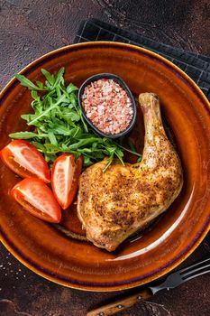 Poultry dish - roasted chicken legs with vegatables salad. Dark background. Top view.