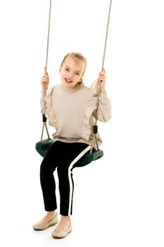 Beautiful little girl swinging in the studio on a swing. Concept of a happy childhood, family well-being.