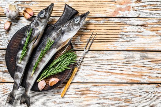 Raw whole icefish with herbs. White Wooden background. Top view. Copy space.