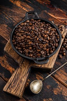 Dark roasted Coffee beans in a pan. Dark wooden background. Top view.