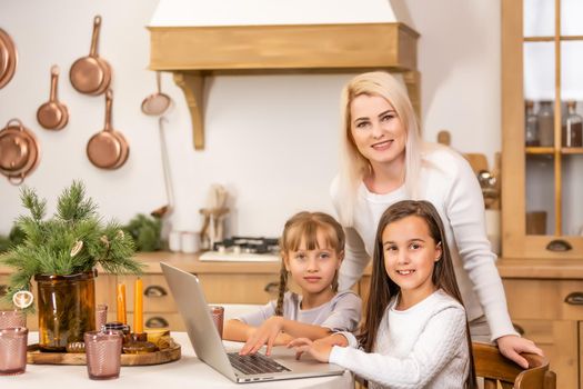 Two little girls watching online school while sitting at table dining room table.