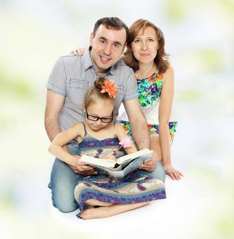 Very positive young family, mom dad and daughter reading a book with enthusiasm.