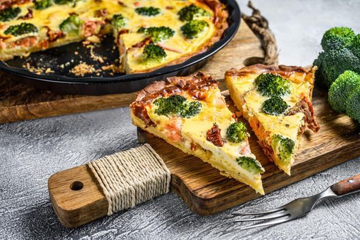 Sliced tart with salmon, broccoli and cream on a wooden cutting board. White background. Top view.