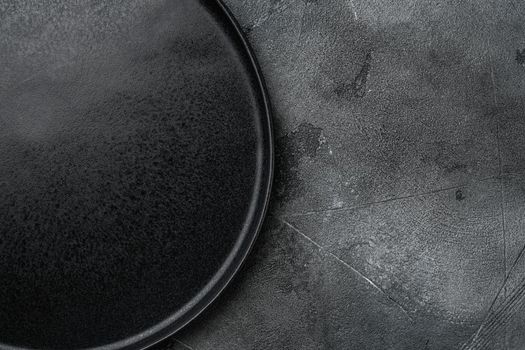 Top view of black plate set, on gray stone table background
