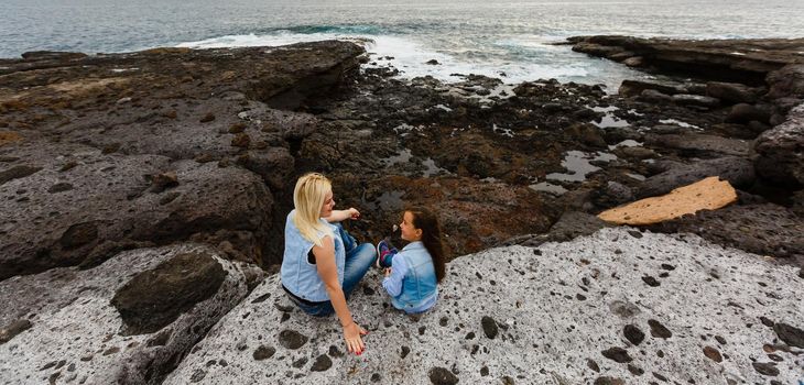 mother and daughter are walking near the ocean on the island of tenerife.