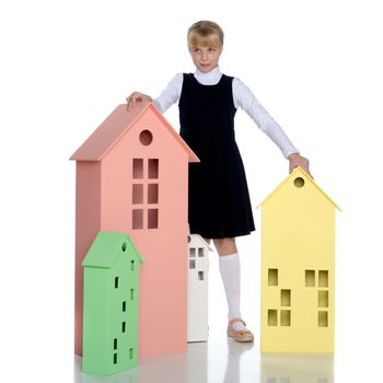 A cute little girl is playing with wooden houses. The concept of family happiness, play, creative development of the child.