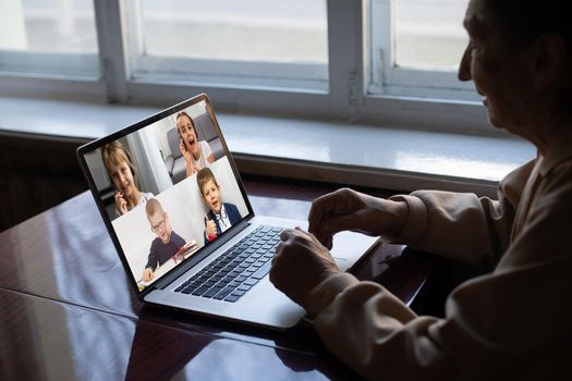 Close-up Of Grandmother Video Conferencing With Her Family On Laptop At Home.