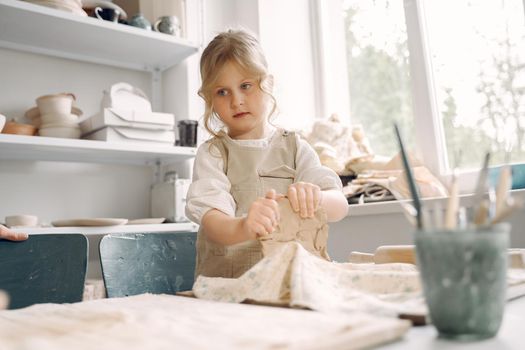 Portrait of little girl painting a ceramic model at school. Concept for art and creative education. Kids concept hobby.