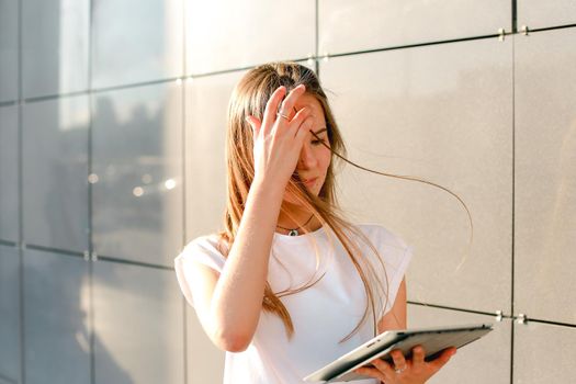 Female work, negotiating, solves problems, browsing touch looking tablet. Young beautiful business woman entrepreneur with long hair wearing suit standing near center technology sun.