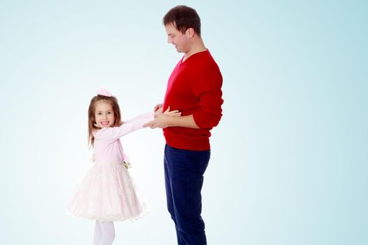 Cute little long-haired girl in a smart pink dress , reaches out to his dad.