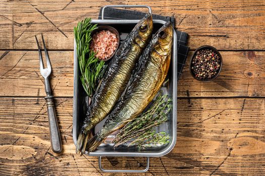 Smoked marinated herring fish in kitchen tray with herbs. Wooden background. Top view.