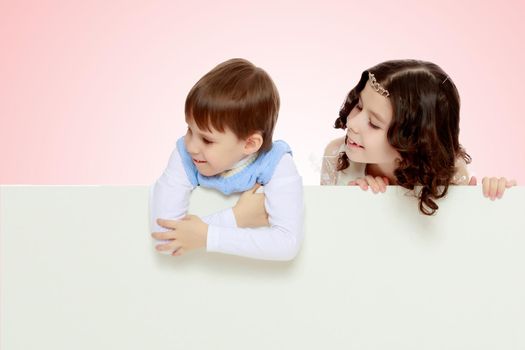 A boy and a girl peeping from behind the white banner.Children look to the side.Pale pink gradient background.