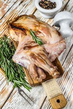 Oven Baked whole lamb shoulder on a cutting board. White wooden background. Top view.