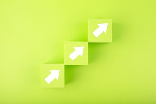 Ladder career, sales or business growth and success path concept. Green blocks as step stairs with white arrows up on bright background with copy space
