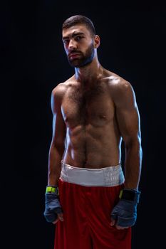 Boxing man ready to fight. Boxer with strong hands and clenched fists in blue straps against a black background. Strength and motivation. Studio shot