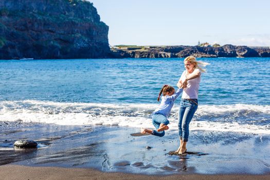 Family holiday on Tenerife, Spain. Mother with daughter outdoors on ocean. Portrait travel tourists - mom with daughter. Positive human emotions, active lifestyles. Happy young family on sea beach