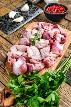 Raw uncooked chicken gizzards, stomach on a cutting board. wooden background. Top view.