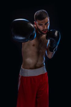 The boxer is ready to deal a powerful blow. Photo of muscular man on black background. Strength and motivation.