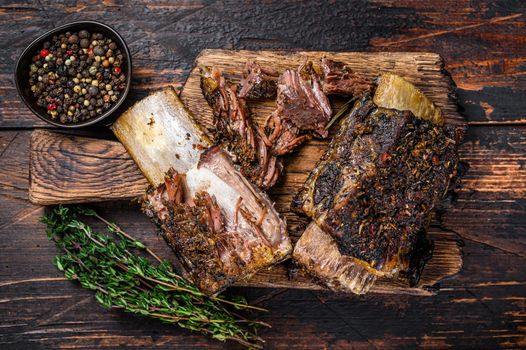 BBQ short chuck beef ribs with herbs and meat cleaver. Dark wooden background. Top view.