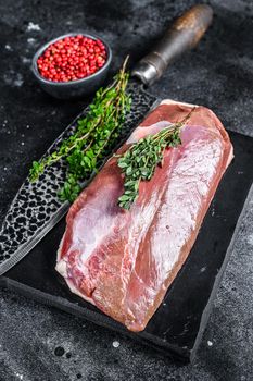 Raw duck breast fillet on a marble board. Black background. Top view.