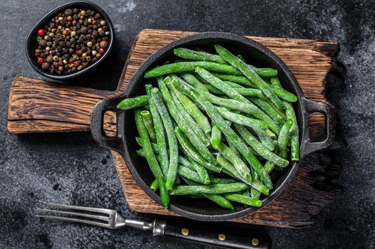 Frozen green beans in a pan. Black background. top view.