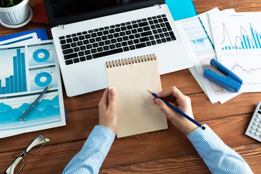 close-up, female hands with notebook and pencil. Business woman working at the table in the office