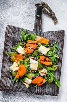 Autumn salad with baked pumpkin and brie cheese. Healthy vegan food concept. White background. Top view.