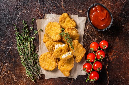 Pile of crispy homemade baked chicken nuggets with ketchup. Dark background. Top view.