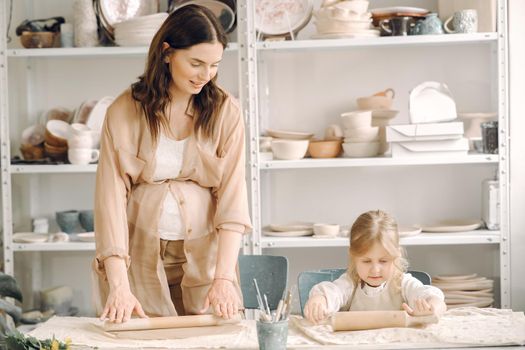 Woman and girl kneading clay. Family make art product at table in pottery workshop. Mother with daughter.