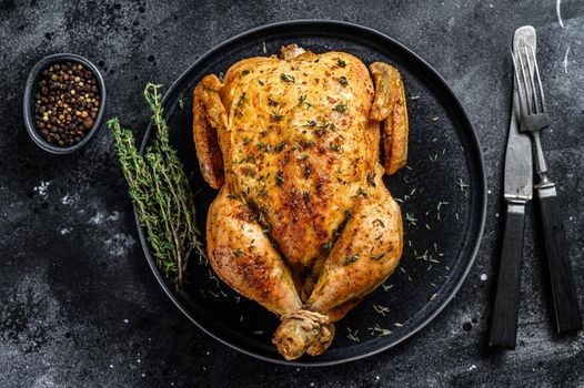 Homemade whole baked chicken rotisserie with thyme. Black background. Top view.