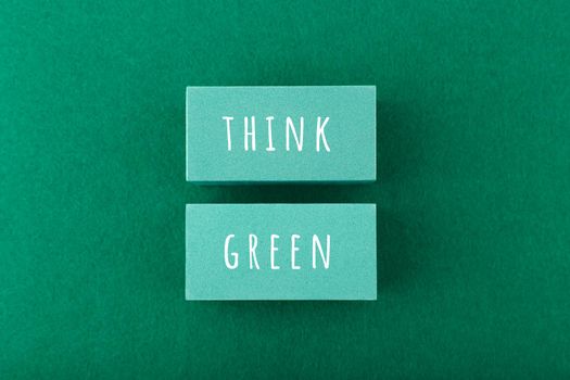 Modern minimal flat lay composition with think green inscription against green background. Concept of go green, recycle, reduce, reuse, zero waste and eco friendly lifestyle