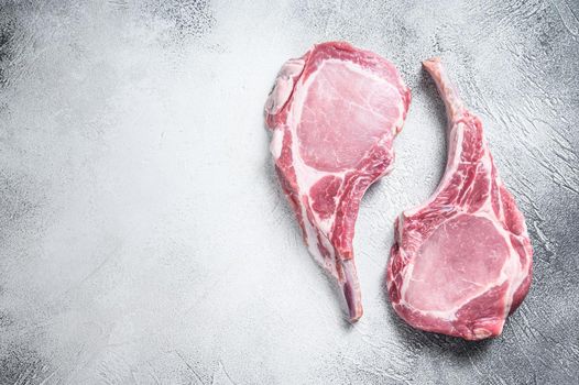 Raw dry aged tomahawk pork chop steak. White background. Top view. Copy space.