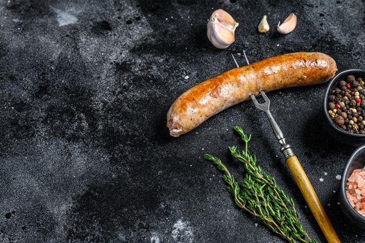 Pork Sausage bbg grilled with spices and herbs on a meat fork. Top view. Black background. Copy space.