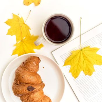 croissant with coffee on the background of a heap of books. Student eating breakfast, study concept.