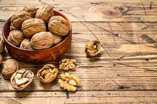 Walnuts in a wooden plate and walnut kernels. Gray background. Top view. Copy space.