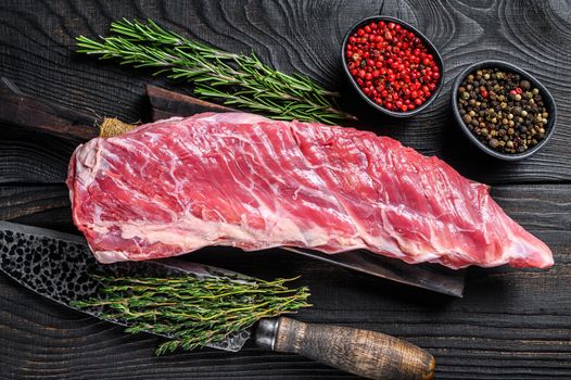 Raw veal calf short spare rib meat with butcher knife. Black wooden background. Top view.