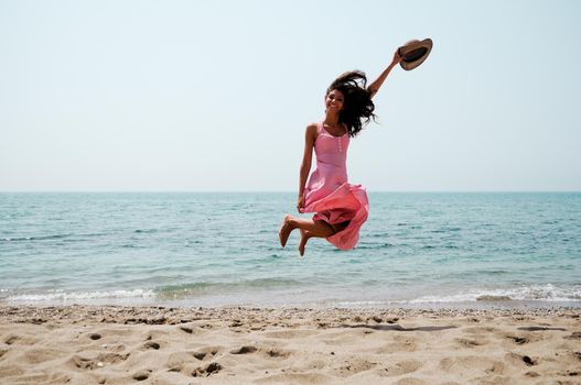 Portrait of a beautiful woman with long pink dress on a tropical beach