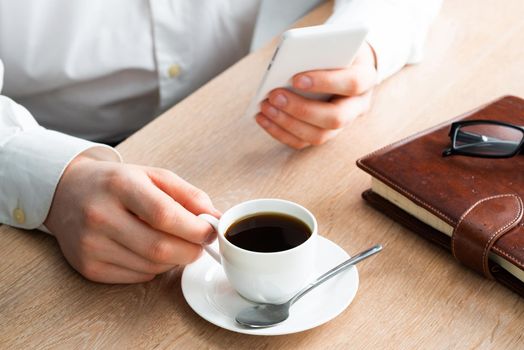 Businessman surfing internet on smartphone as sit in cafe with cup of coffee. Financial specialist working with online analytics. Business application and mobile technology. Internet communication