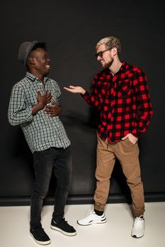 Studio lifestyle portrait of two best friends hipster boys going crazy and having great time together. On black background. Full-length photo