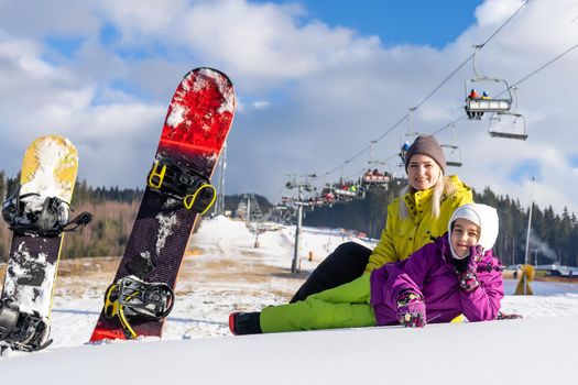 mother and daughter with snowboards in a mountain resort