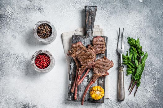 Roasted chops steaks of lamb mutton on a wooden board. White background. Top view.