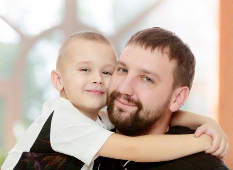 Happy family. Dad and son hug each other.In a room with a large semi-circular window.