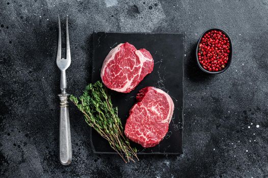 Prime Raw Fillet Mignon tenderloin steaks with thyme. Black background. Top view.