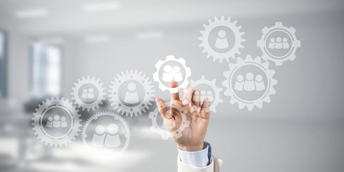 Close of businesswoman hand touching gears on screen with finger and office at background