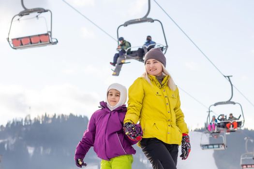 Mother and daughter with snowboards are playing in the snow