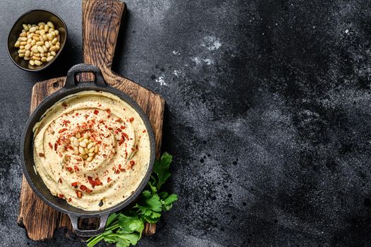 Hummus paste with chickpea and parsley in a bowl. Black background. Top view. Copy space.