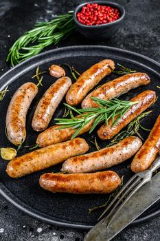 Grilled sausages with rosemary herbs, beef and pork meat. Black background. Top view.