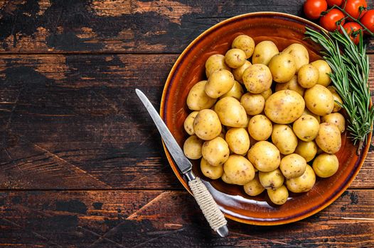 Raw baby mini Potatoes. Dark wooden background. Top view. Copy space.