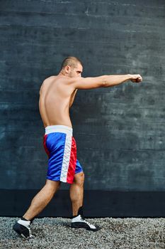 Boxer shorts in athletic training outdoors. He stands in a fighting stance. The young man works off a blow