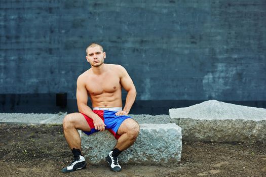 The sportsman has a rest, sitting on a rock. He looks into the camera